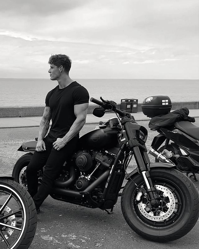 Luke beside a motorbike by the sea, black and white (Instagram post)